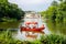 Red gondola with tourists cruising on the lake with The Palace on the Isle in Warsaw`s Royal Baths Park.