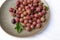 Red gooseberry berries in a clay plate on a white background. Collected in the summer from a gooseberry bush.