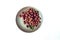 Red gooseberry berries in a clay plate on a white background. Space for the text. Collected in the summer from a