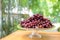 Red grape on the step glass plate stand alone on the wood table in the outdoor garden field blur bokeh