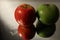 Red and green apples on a mirror