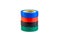 Red, green and blue adhesive insulating electrical tape reels stack isolated on white background.