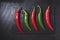 Red and green chillies on blackboard base on black background. Top view. Gastronomy and cooking condiments