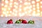 Red and green ornaments in snow with bokeh background