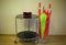 Red and green umbrellas in big glass vase near coffee table with three candle glasses. Home design. Office design.