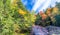 Red, green and yellow trees of New England with creek in October. Foliage season, USA