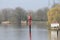 Red guiding post in the river Hollandsche IJssel to mark the safe waterway in the water.