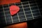 Red Guitar Pick Between the Strings of an Old Acoustic Guitar