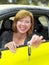 Red hair happy and smiling girl on her 20s or 30s sitting proud at driver seat holding and showing car key in new automobile buyin