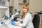 Red hair woman lab technician looking through microscope analyse blood