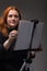 Red hair woman painting. Portrait of an artist against gray background