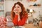 Red-haired appealing girl smiling broadly working in art studio