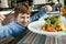 Red haired boy with forks eating salad