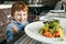 Red haired boy with forks eating salad