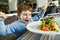 Red haired boy with forks eating salad