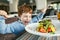 Red haired boy with forks eating salad