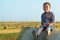 A red-haired boy sits on top of a straw bale on a wheat field