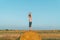 A red-haired boy stands with hands up on top of a straw bale on a wheat field