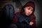 A red-haired boy, a twelve-year-old teenager, with an anxious expression on his face, sits on the stairs inside an apartment build