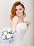 Red-haired bride in a wedding dress holding wedding bouquet, bright unusual appearance. Beautiful wedding hairstyle and