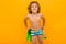 Red-haired curly boy holds swimming flippers over yellow background