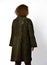 Red-haired curly woman poses with her back to us in brown sheepskin coat with karakul collar and butterfly embossed