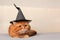 red haired disgruntled cat with yellow eyes lies gray blanket in black witch hat. concept Halloween, holiday. copy space