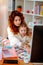 Red-haired fashion designer working on computer sitting with daughter