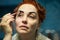 red-haired forty-year-old woman paints her eyebrows with paint in the bath