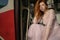 Red haired ginger beautiful young woman sitting on steps of an old red Soviet tram