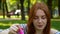 Red-haired girl blows soap bubbles in the park