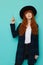 Red haired girl in dark checkered coat and black hat is pointing up