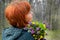 The red-haired girl dreamily looks away and holds a bright spring bouquet