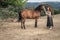 A red-haired girl feeds a brown horse and talks to it