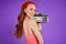 Red-haired girl with freckles stands with portable audio player, looks playfully in camera