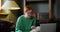 A red-haired girl with glasses starts video chat on a laptop, sitting on a sofa