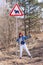 Red-haired girl indulges near a road sign depicting a cow on a forest background.