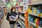 Red-haired girl in a medical mask buys toilet paper in a supermarket.