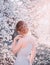 Red-haired girl in a modest, gray dress in rustic style. Portrait of the bride against the background of a flowering