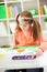 Red-haired girl with pigtails drawing with watercolors on the pa