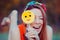 Red haired girl playing with yellow emoji candy on a stick