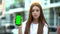 Red-haired girl showing smartphone with green screen, free navigation app