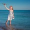 Red-haired girl is standing in blue sea and is happily playing with a toy orange plane