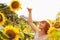 Red-haired girl is standing next to a tall sunflower, a woman measures the height of a sunflower, her hand is lifted up