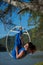 Red-haired gymnast in a blue suit doing the difficult exercises at the air ring in nature