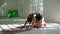 Red-haired healthy caucasian woman practicing yoga on the mat in the white large room. Young woman in sports clothing