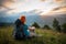 Red-haired lady with backpack in the mountains at sunset