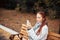 Red-haired middle-aged woman with a smartphone in her hand sits on a bench in the Park and communicates in social networks