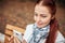 Red-haired middle-aged woman with a smartphone in her hand sits on a bench in the Park and communicates in social networks