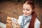 Red-haired middle-aged woman with a smartphone in her hand sits on a bench in the Park and communicates in social networks